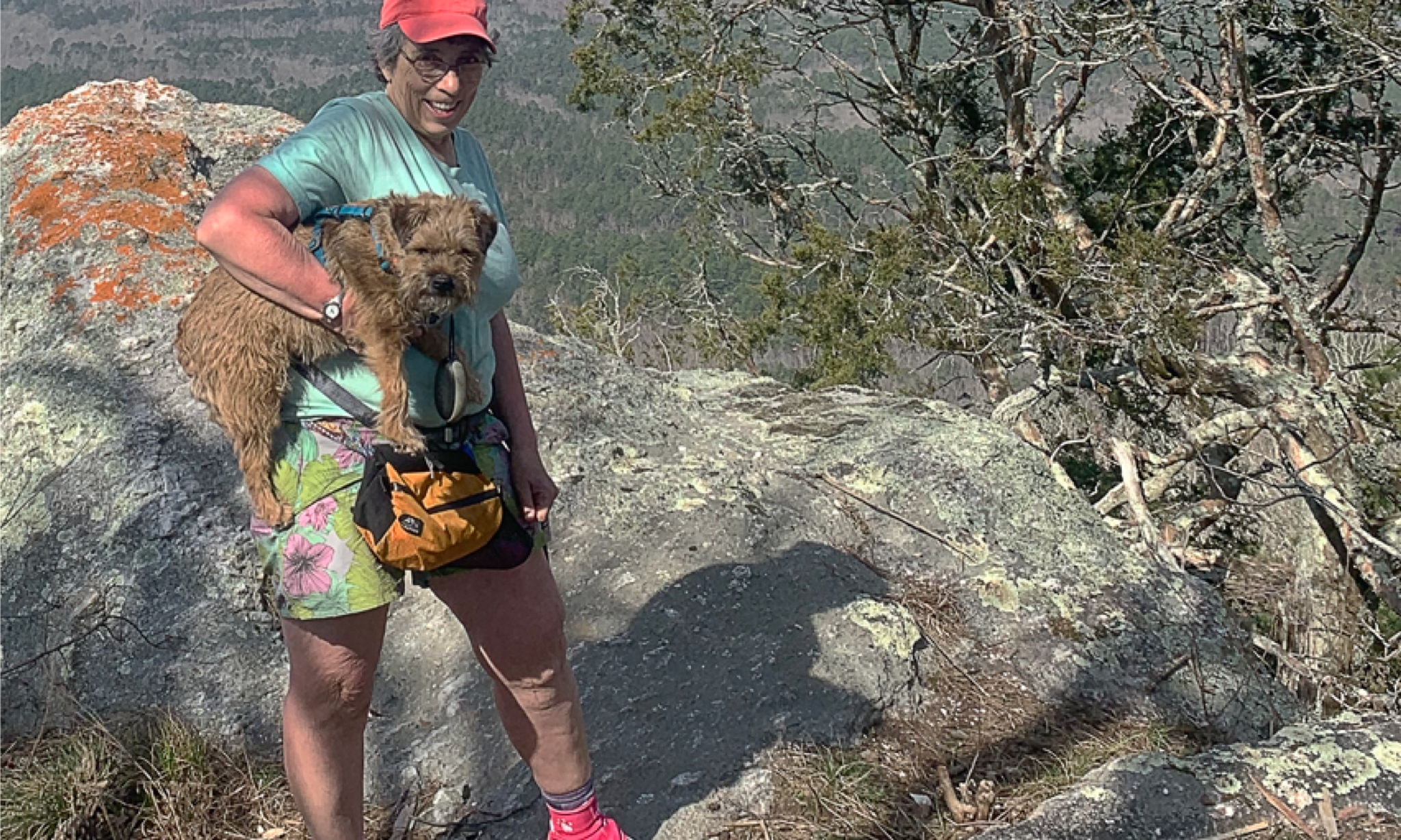 A woman poses with her small dog at a lookout point along the Cranberry Lake 50 mile hike