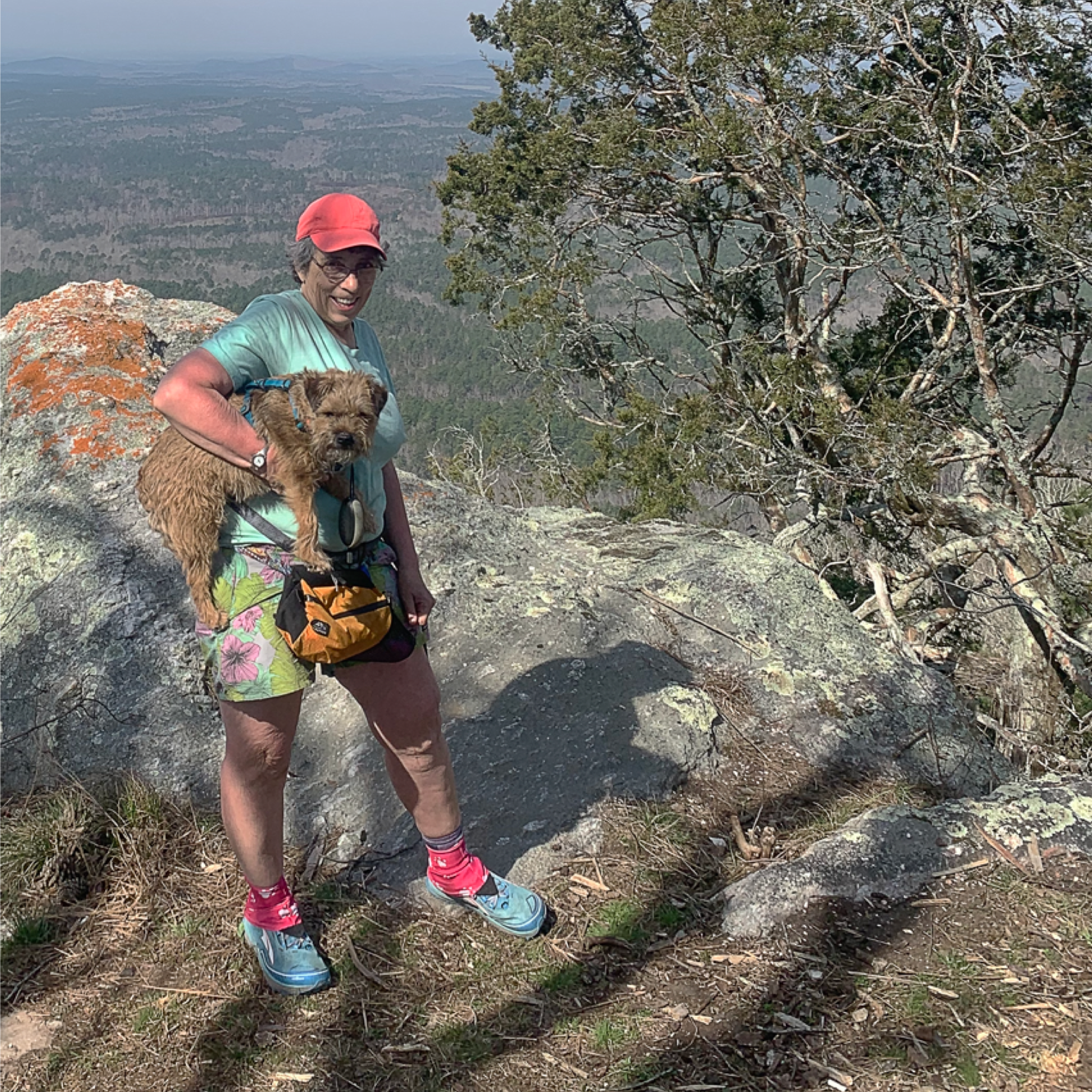 A woman poses with her small dog at a lookout point along the Cranberry Lake 50 mile hike