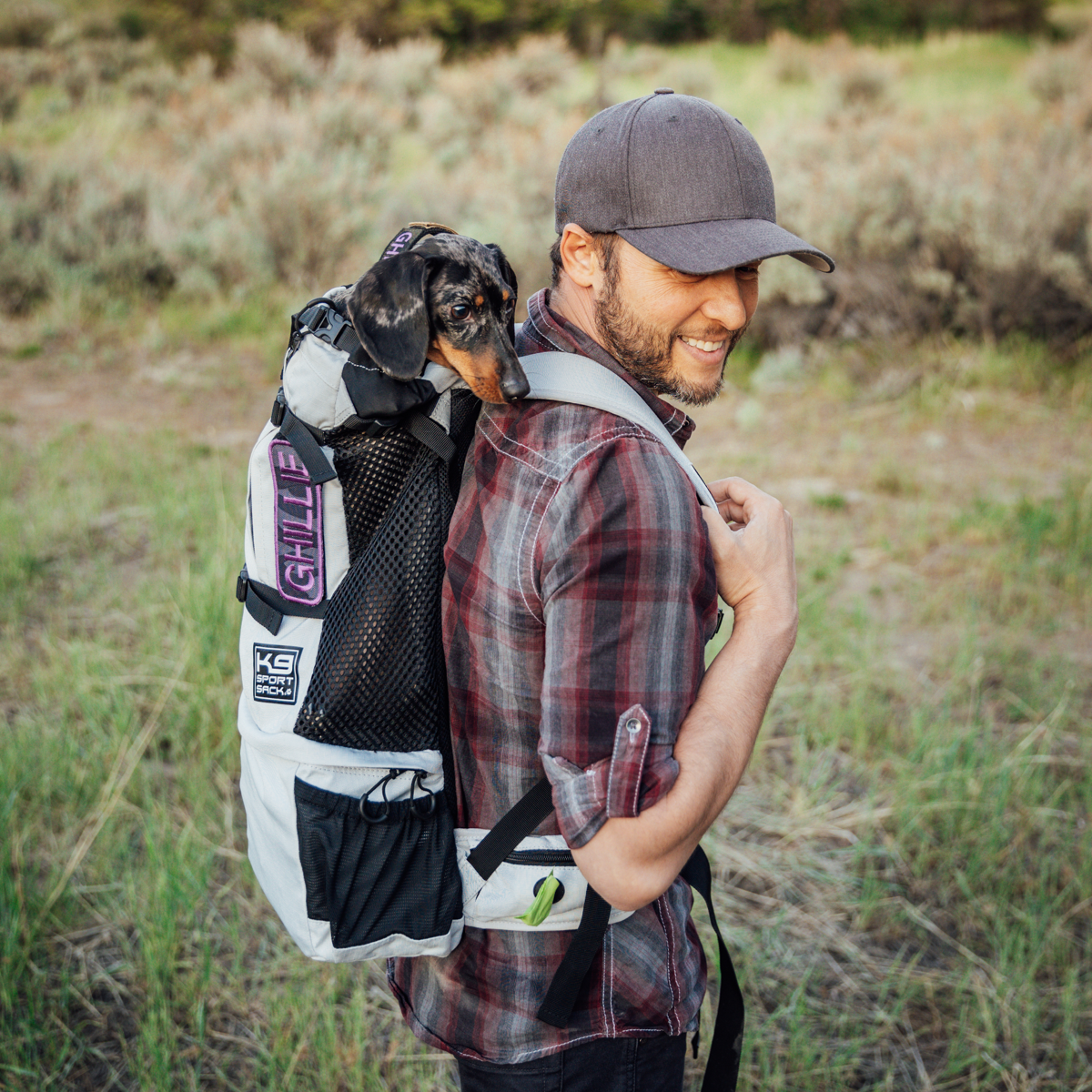 A young man hikes with his dog in a Knavigate backpack dog carrier